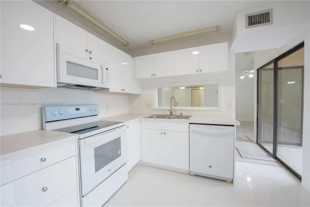 a kitchen with white cabinets and white appliances