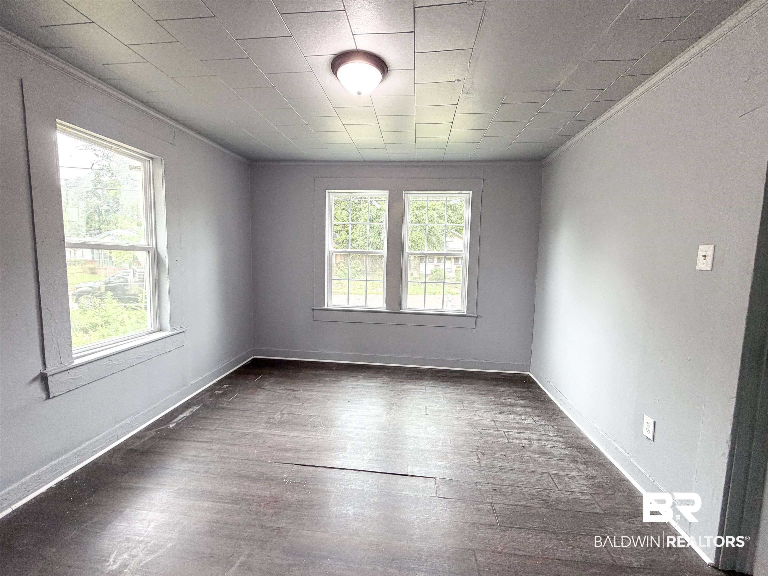 38 Flock Avenue Mobile, AL 36610 - Photo 19 of 27 Room featuring wood-finish flooring, two large windows, a central flush-mount light fixture, and light gray painted walls
