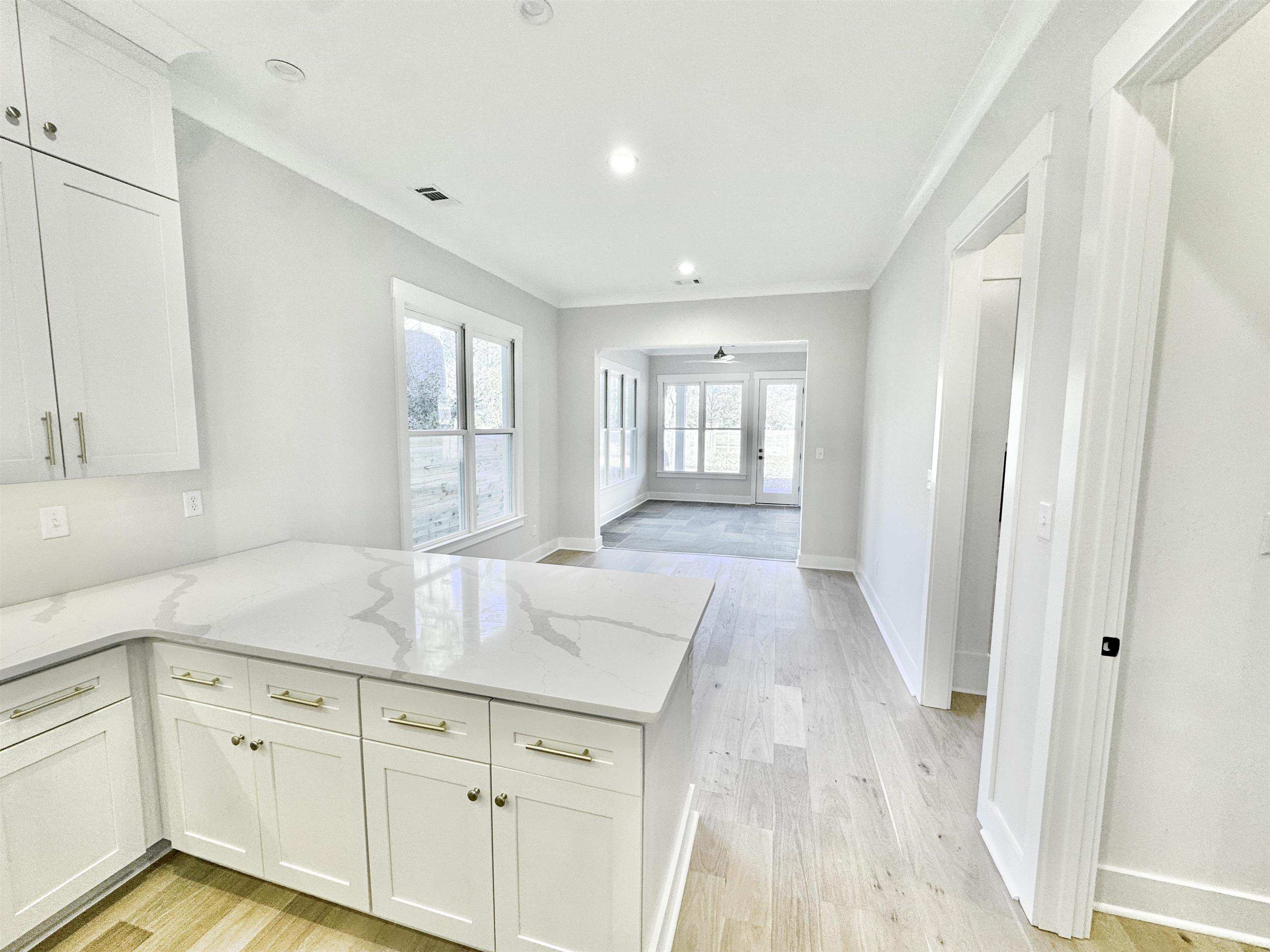 354 Avon Road Memphis, TN 38117 - Photo 12 of 40 Kitchen with white cabinets, light stone countertops, light wood-style floors, crown molding, and a peninsula