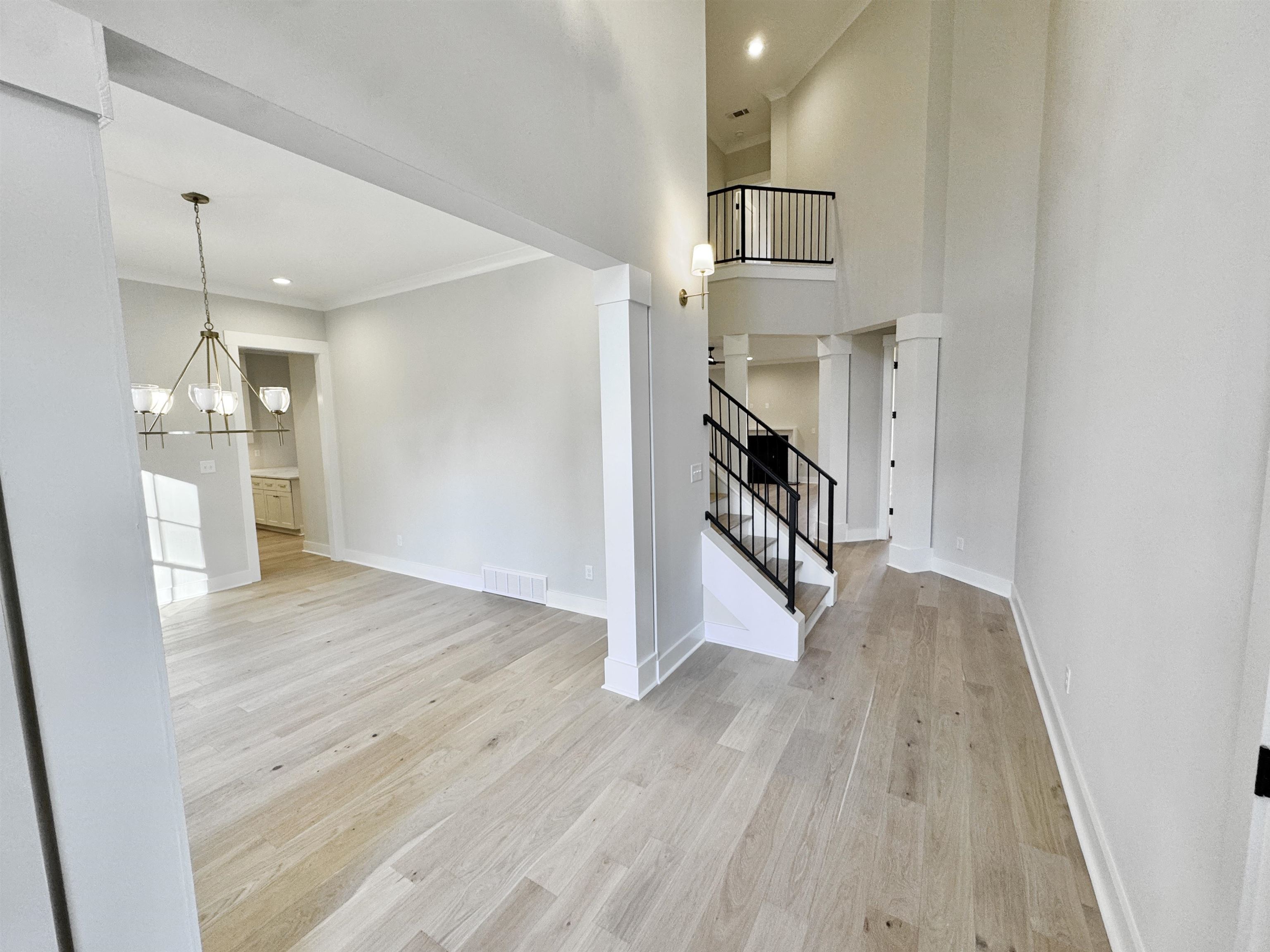 354 Avon Road Memphis, TN 38117 - Photo 4 of 40 Unfurnished living room featuring light wood finished floors, a chandelier, a towering ceiling, stairway, and recessed lighting