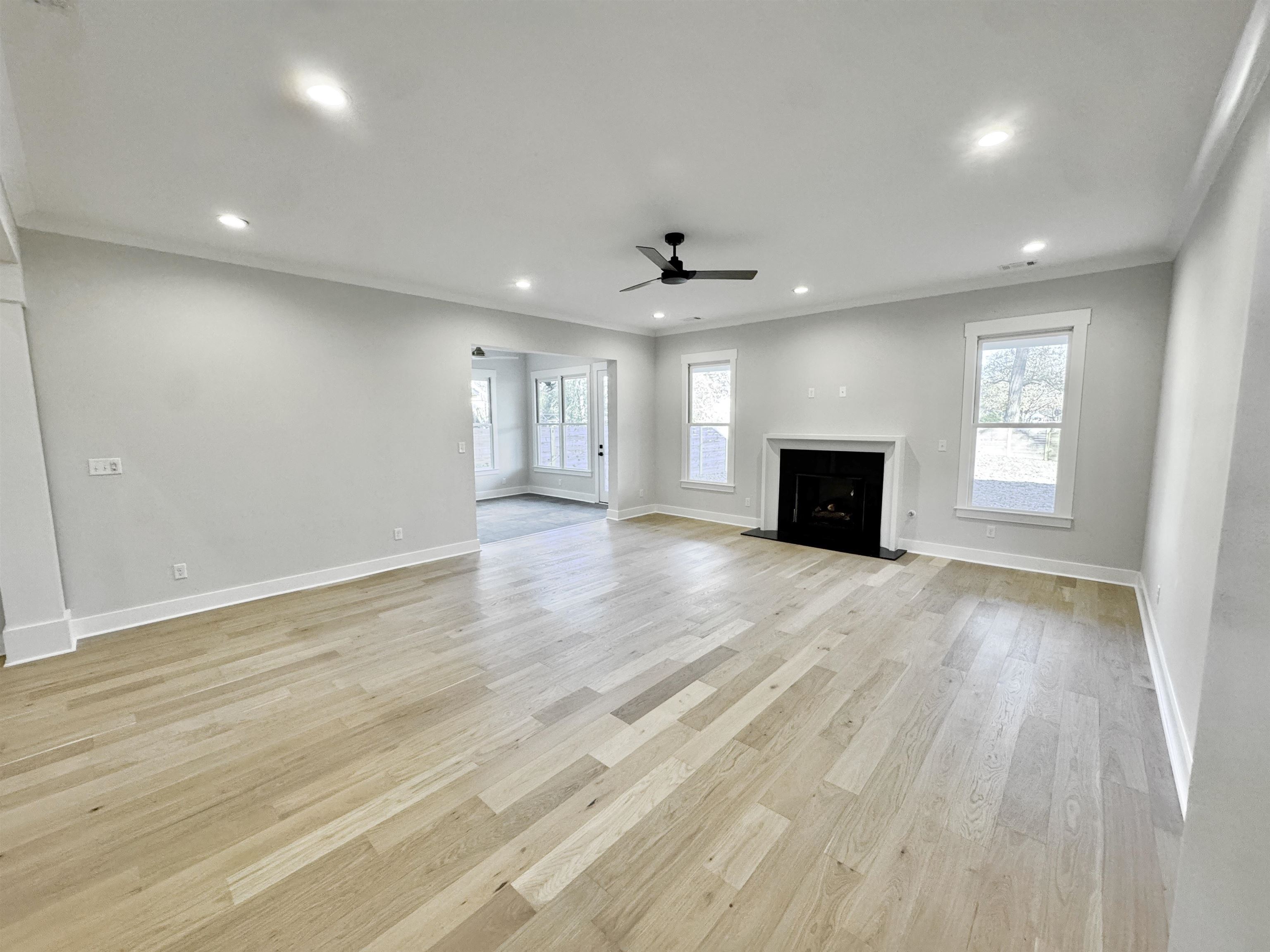 354 Avon Road Memphis, TN 38117 - Photo 7 of 40 Unfurnished living room with a fireplace, ornamental molding, plenty of natural light, light wood-style flooring, and a ceiling fan