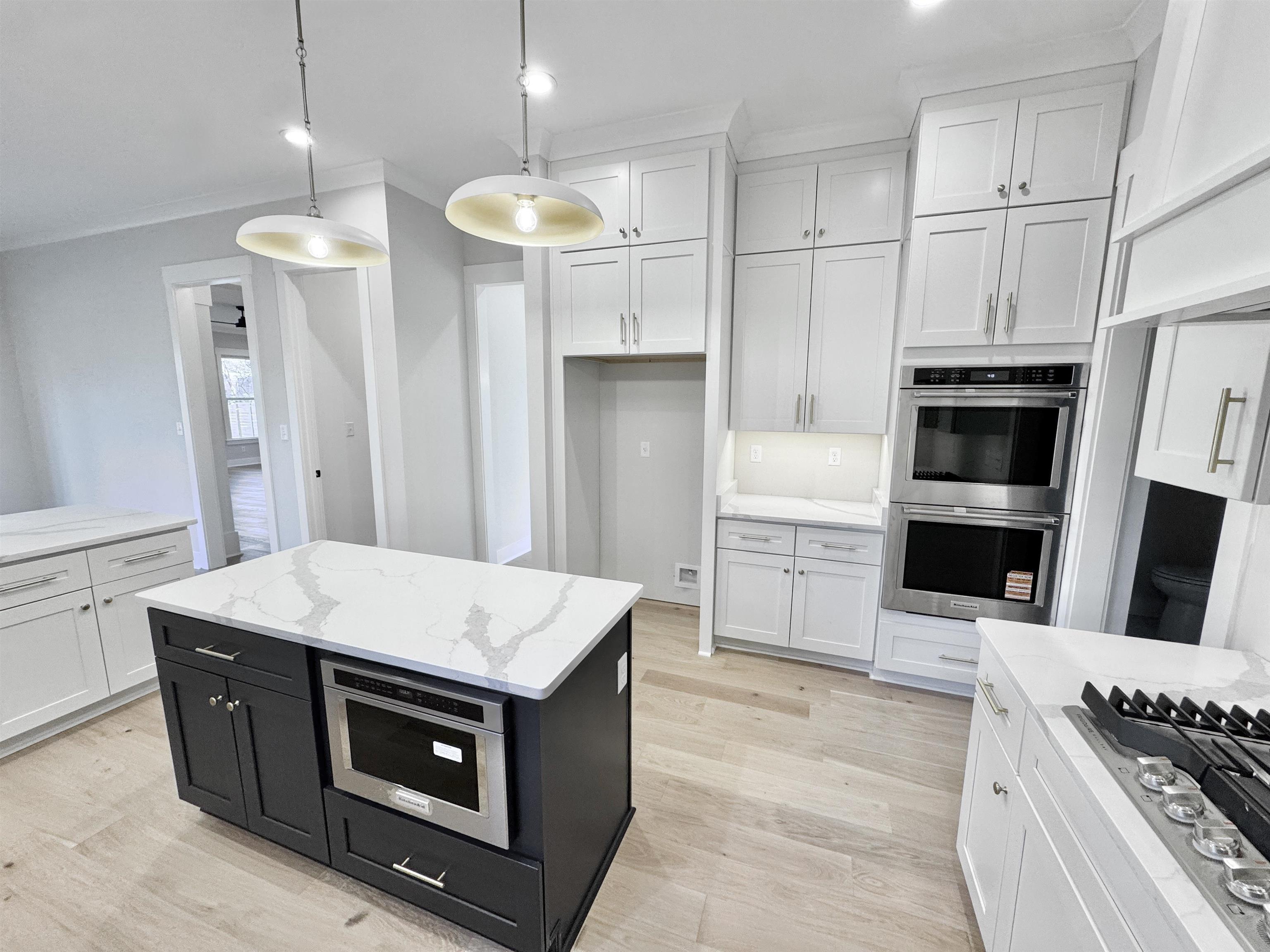 354 Avon Road Memphis, TN 38117 - Photo 10 of 40 Kitchen with dark cabinetry, a center island, ornamental molding, appliances with stainless steel finishes, and light stone counters