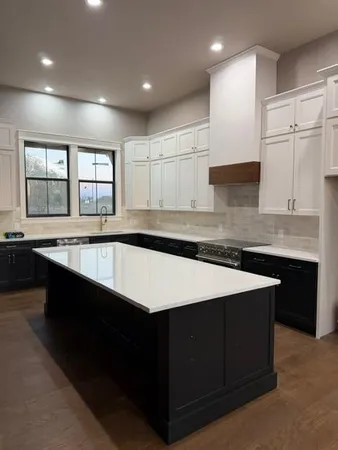 a kitchen with a sink dishwasher a stove and white cabinets