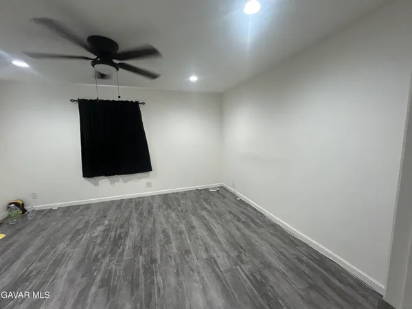 an empty room with wooden floor and a ceiling fan