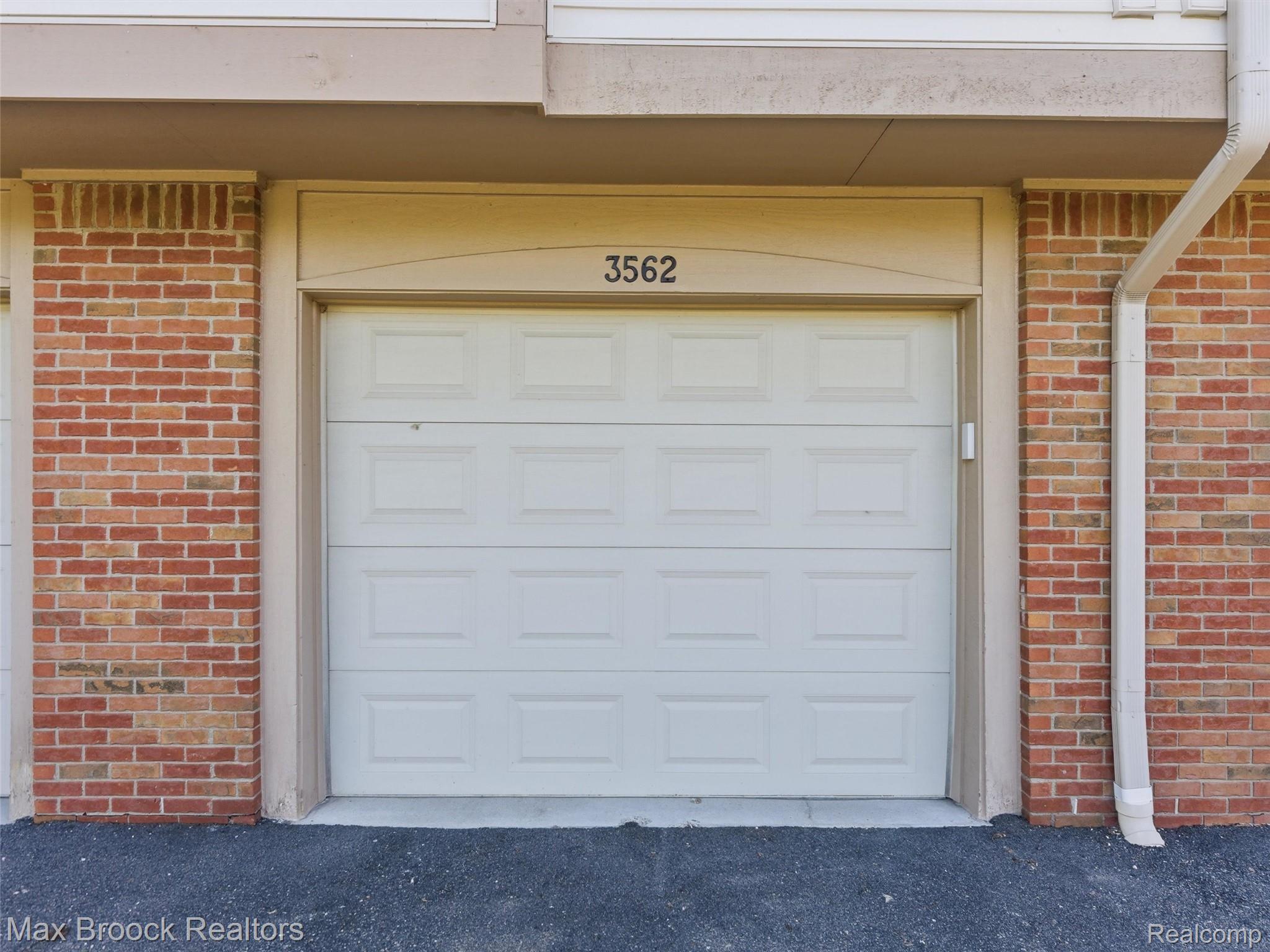 3562 Tremonte Circle Rochester, MI 48306 - Photo 26 of 33 Single-car garage with a paneled door, brick exterior accents, and a downspout