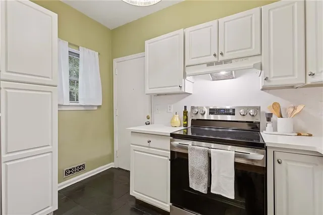 a kitchen with stainless steel appliances granite countertop white cabinets and a stove top oven
