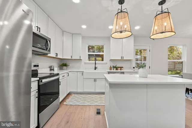 a kitchen with white cabinets stainless steel appliances and window