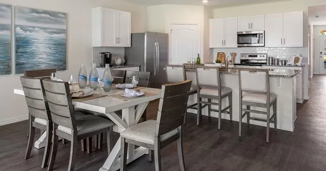 a view of a dining room with furniture wooden floor and a kitchen view