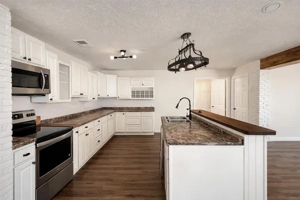 a kitchen with granite countertop a sink stainless steel appliances and cabinets
