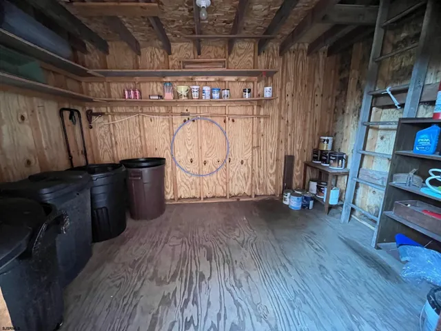a view of an empty room with wooden floor and furniture