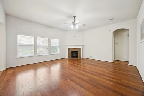 an empty room with wooden floor fireplace and windows