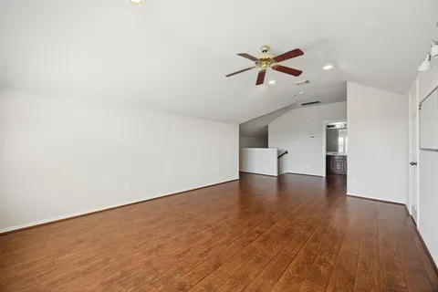a view of empty room with wooden floor and ceiling fan