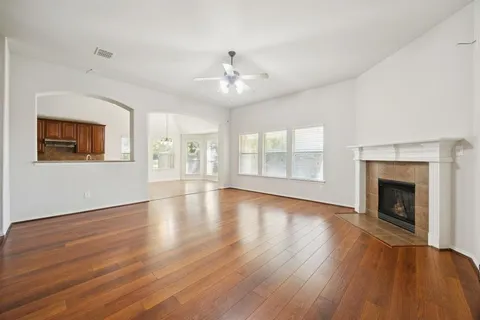 an empty room with wooden floor fireplace and windows