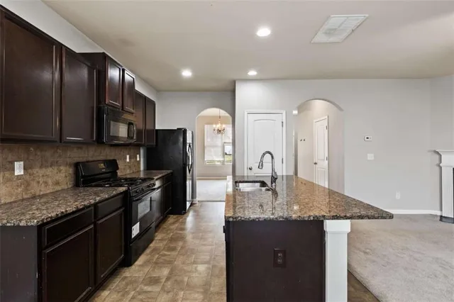 a kitchen with kitchen island granite countertop stainless steel appliances and wooden cabinets