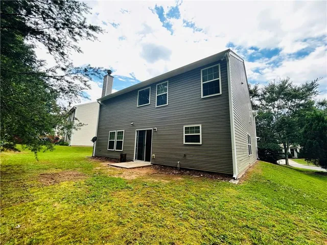 a view of a house with backyard and trees
