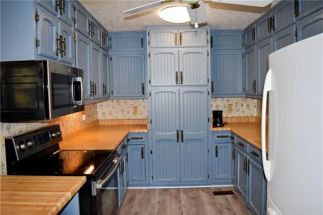a kitchen with stainless steel appliances granite countertop a refrigerator a stove and a sink with wooden floor
