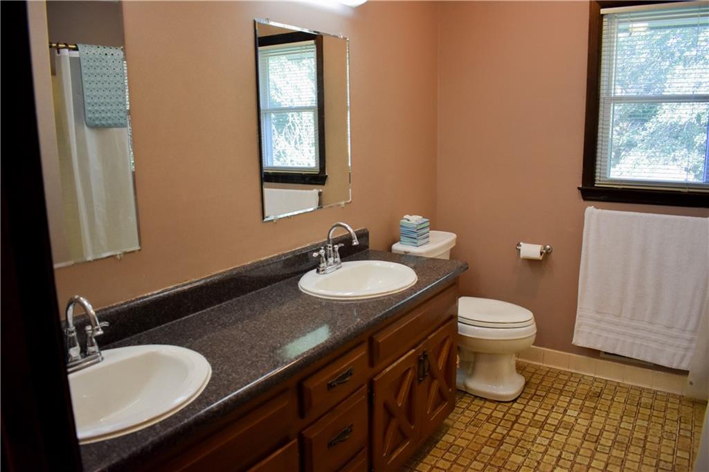 6882 Cowan Mill Road Winston, GA 30187 - Photo 21 of 50 a bathroom with a granite countertop toilet a sink and a mirror