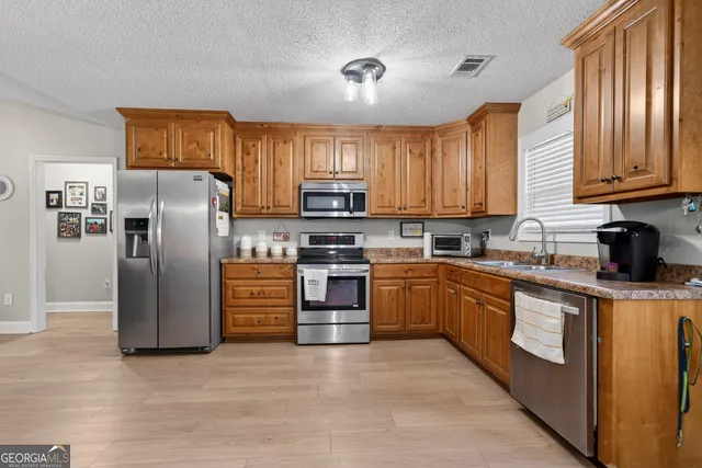 a kitchen with refrigerator a microwave a sink and cabinets
