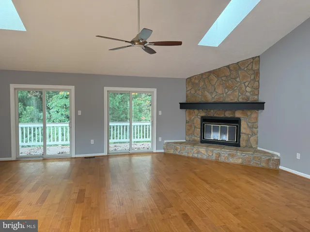 a view of an empty room with wooden floor fireplace and a window