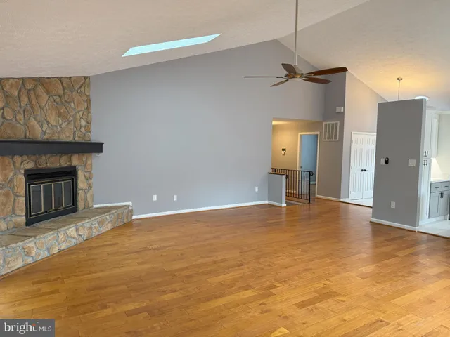 a view of an empty room with a fireplace and a chandelier fan