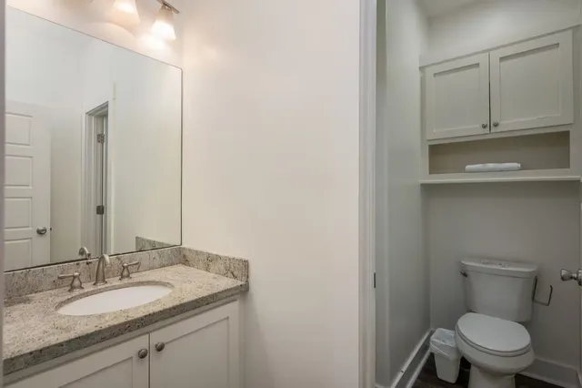 a bathroom with a granite countertop toilet sink and mirror