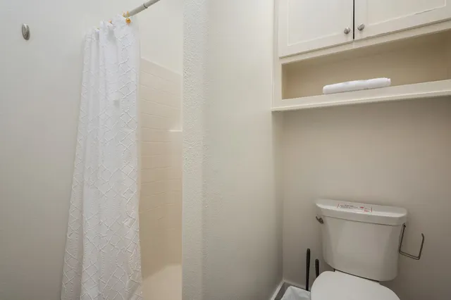 a white toilet sitting next to a shower