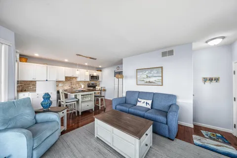 a living room with furniture a flat screen tv and kitchen view