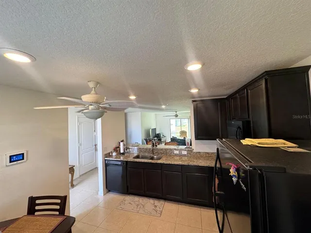 a kitchen with granite countertop cabinets a refrigerator and a sink