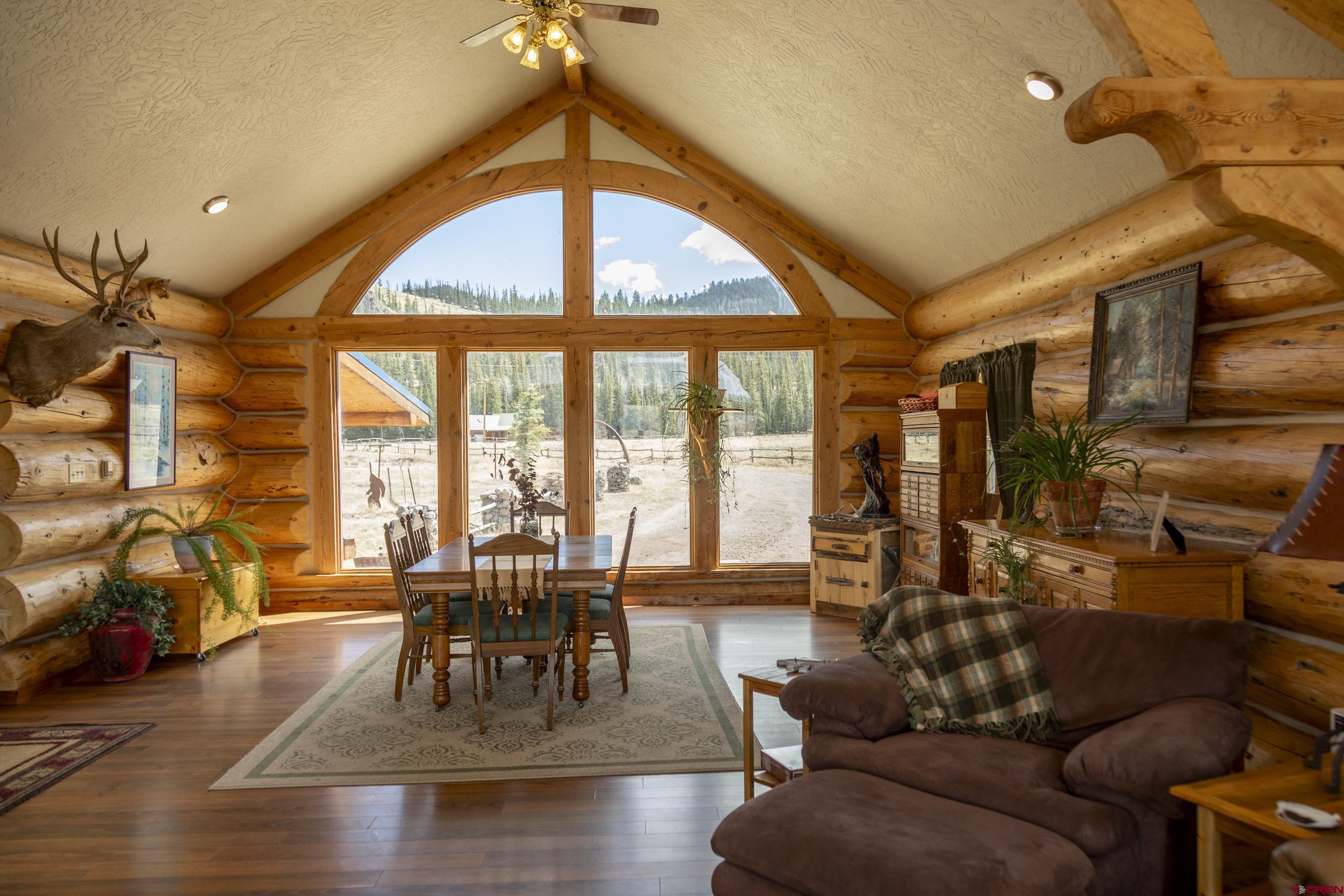 108 Forest Road Creede, CO 81130 - Photo 8 of 32 a dining room with wooden floor a chandelier a glass table and chairs