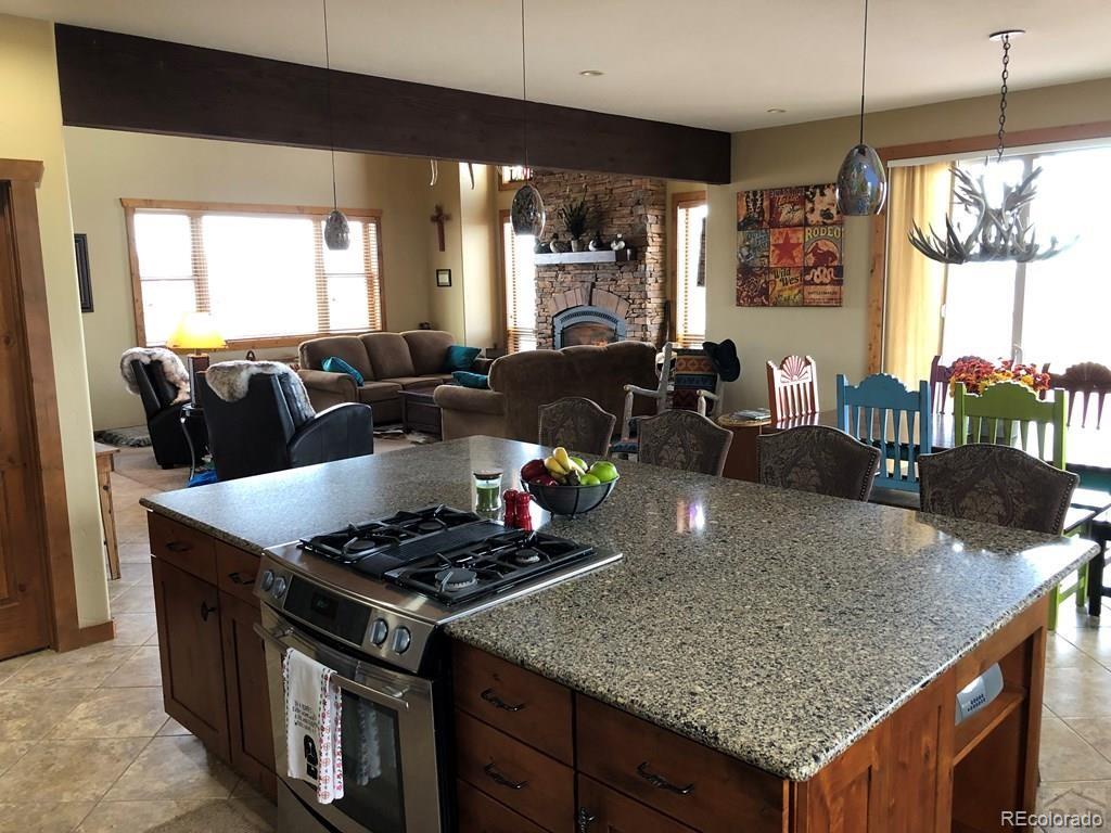 9780 Canyon Point Drive Rye, CO 81069 - Photo 31 of 35 a kitchen with stainless steel appliances granite countertop a stove a chimney a sink and cabinets