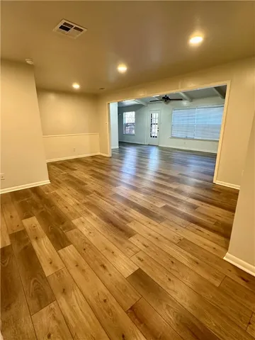 an empty room with wooden floor fan and windows