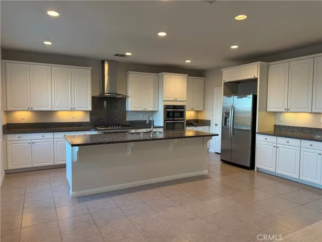 a kitchen with stainless steel appliances granite countertop a refrigerator a stove a sink and a microwave
