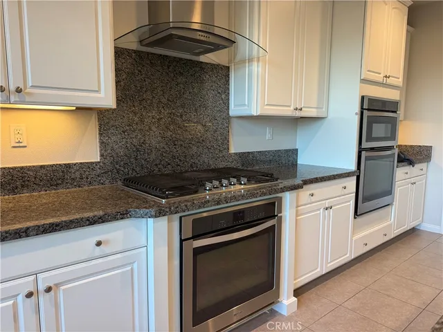 a kitchen with granite countertop white cabinets and stainless steel appliances