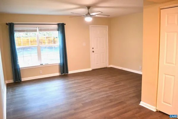 an empty room with wooden floor and windows