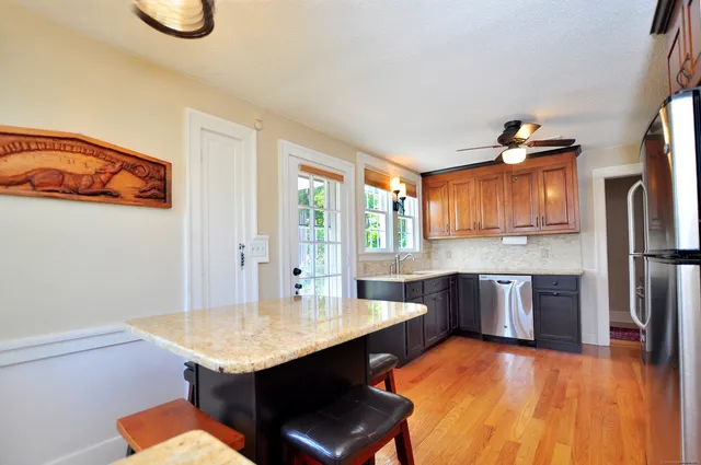 a kitchen with stainless steel appliances granite countertop a kitchen island hardwood floor sink stove dining table and chairs