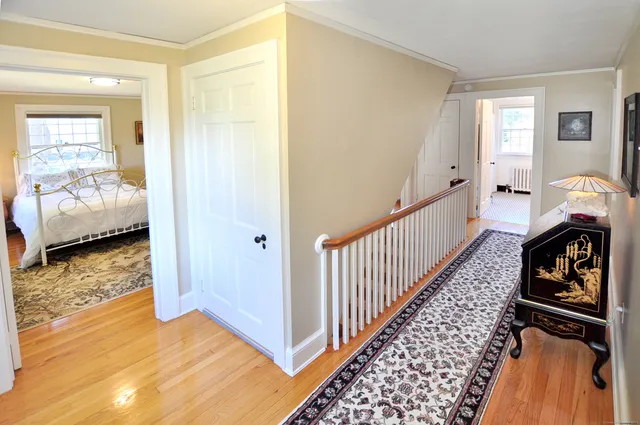 a view of a hallway to a livingroom with wooden floor and windows