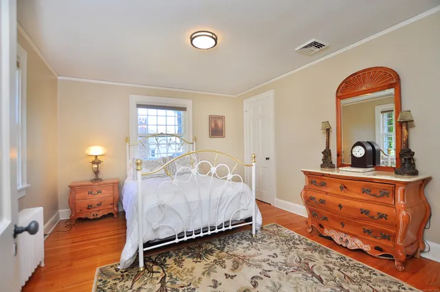 a bedroom with a bed and a dresser next to a window