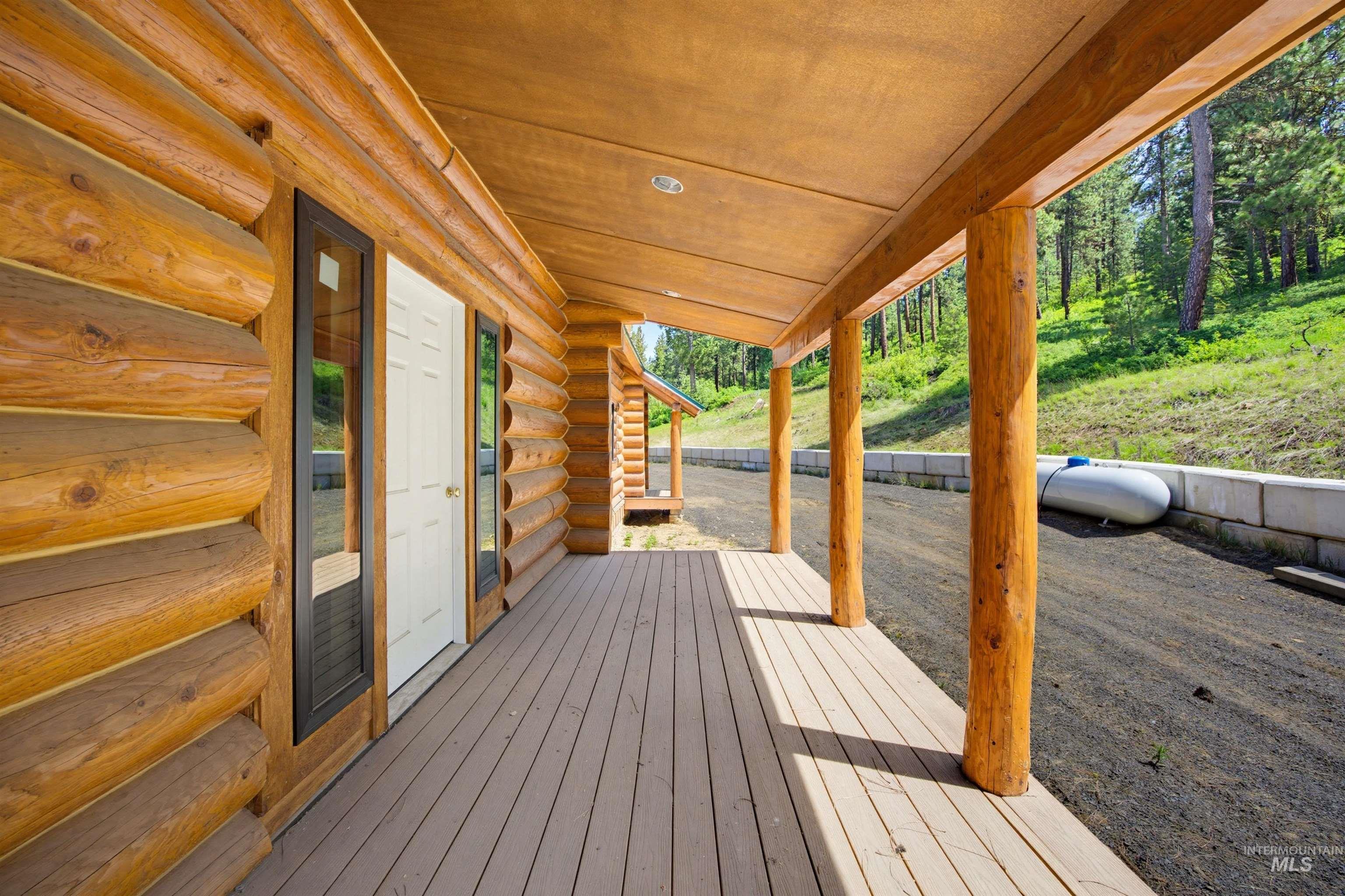 3322 Big Creek Road New Meadows, ID 83654 - Photo 19 of 50 Expansive covered porch featuring a composite deck, log columns, natural wood ceiling, and log cabin exterior walls