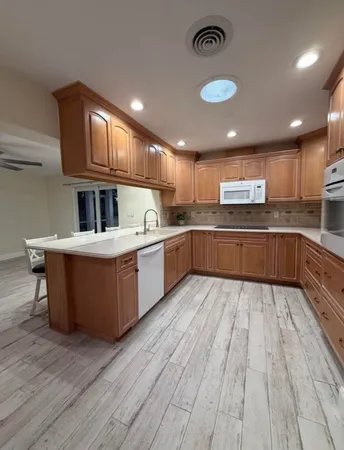 a large kitchen with wooden floors stainless steel appliances a sink and living room view