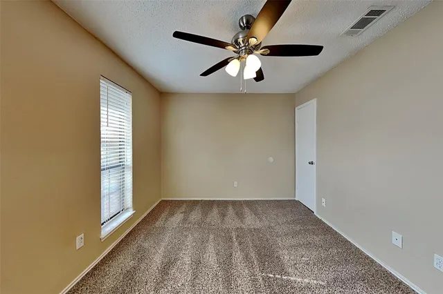 an empty room with a chandelier fan and windows