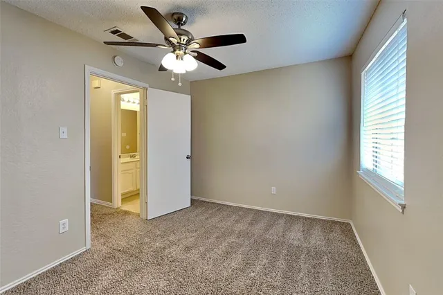 an empty room with a ceiling fan and a window