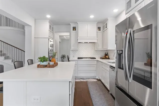 a kitchen that has a refrigerator a sink and white cabinets