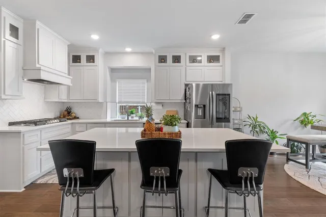 a kitchen with stainless steel appliances granite countertop a table and chairs in it