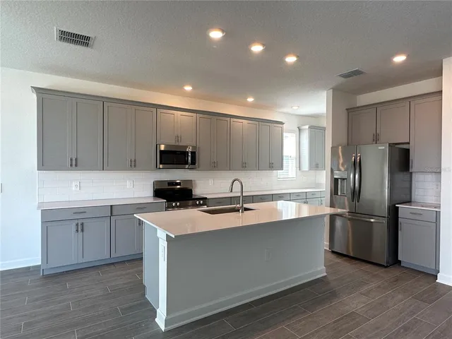 a kitchen with kitchen island a sink stainless steel appliances and cabinets