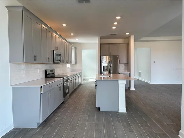 a large kitchen with stainless steel appliances granite countertop a large counter top a sink and a stove