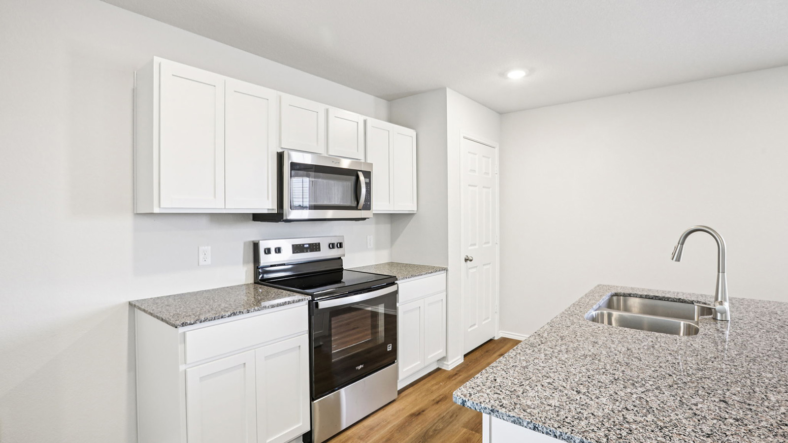 133 Wyatt Way Jarrell, TX 76537 - Photo 4 of 32 Kitchen featuring white shaker cabinetry, stainless steel appliances, granite-style countertops, wood-finish flooring, and a stainless steel double basin sink with a gooseneck faucet