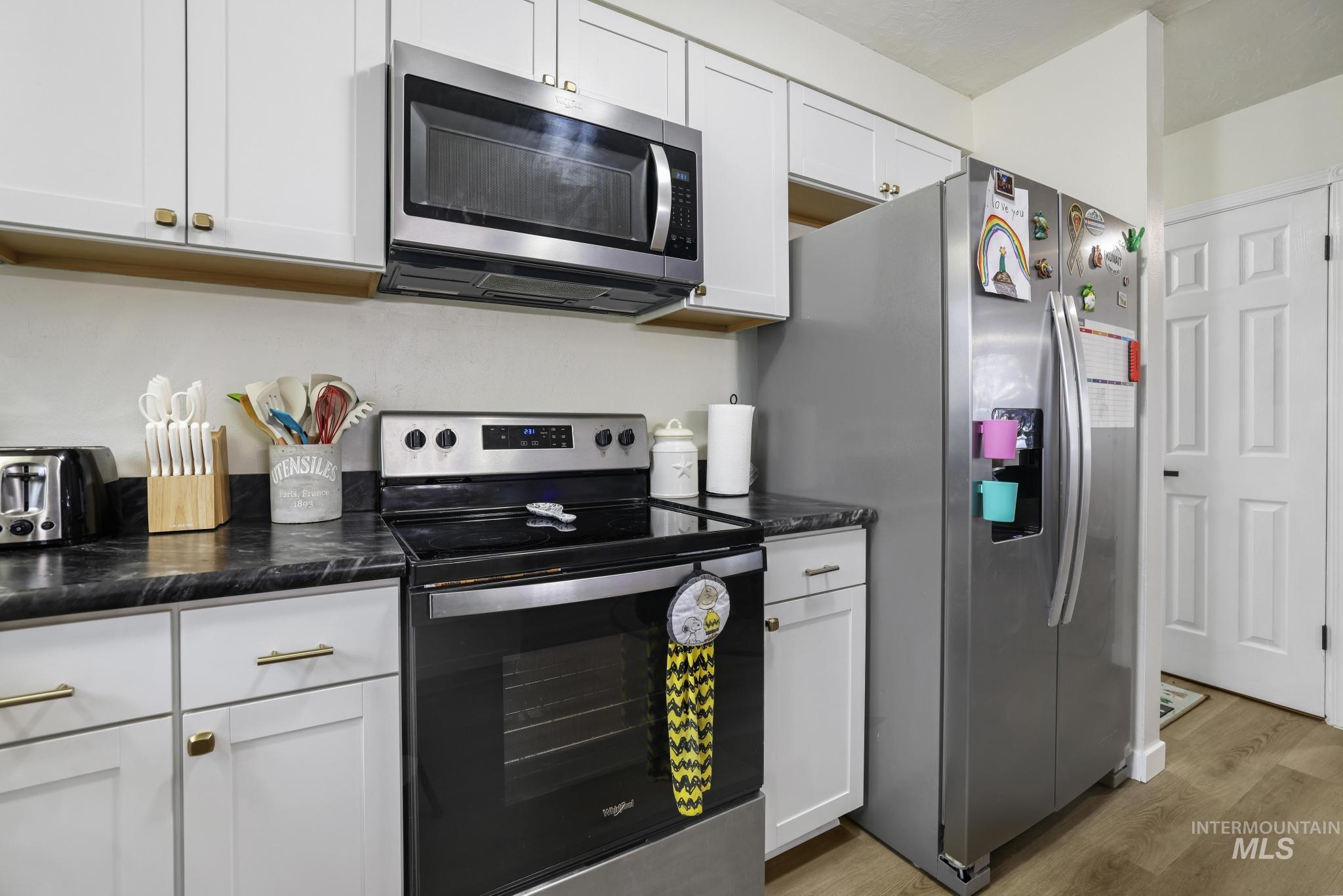 3083 Dickson Avenue Twin Falls, ID 83301 - Photo 7 of 26 Kitchen featuring stainless steel appliances, light wood finished floors, and white cabinets