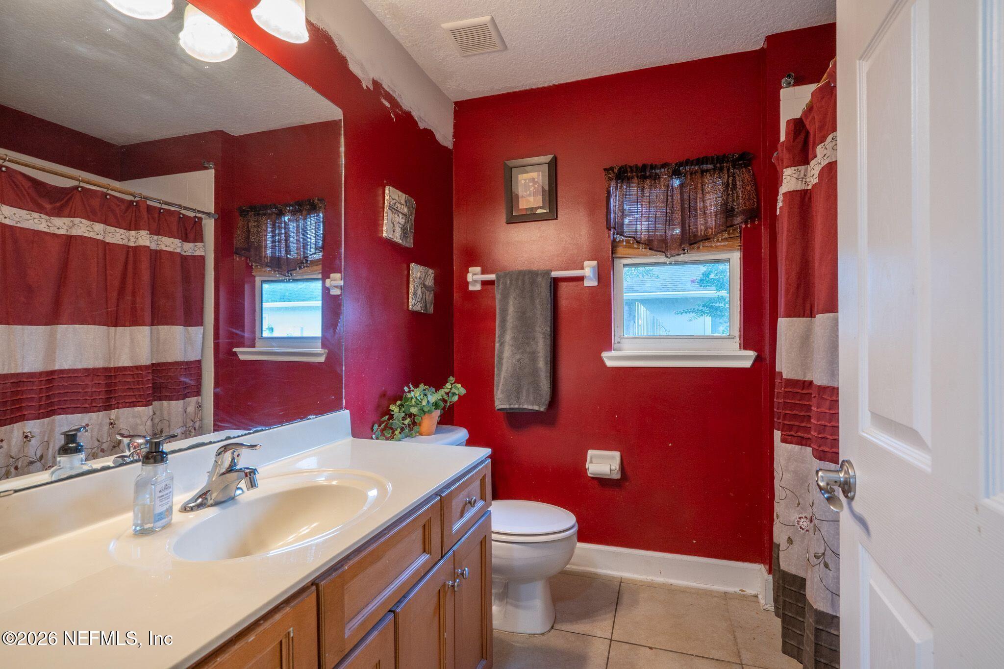 97447 Bluff View Circle Yulee, FL 32097 - Photo 17 of 19 a bathroom with a sink a toilet a mirror and shower curtain