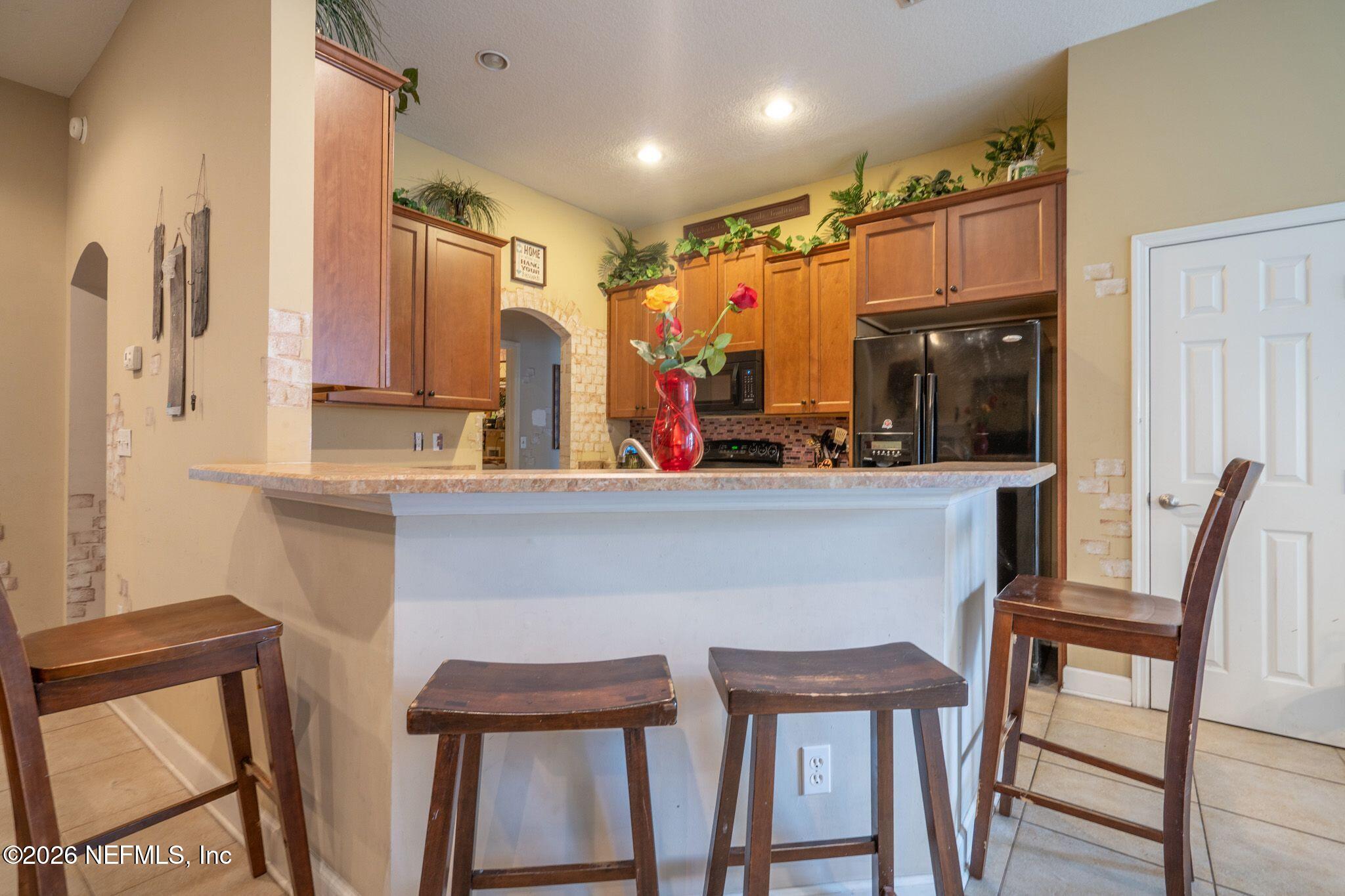 97447 Bluff View Circle Yulee, FL 32097 - Photo 9 of 19 a kitchen with a table chairs sink refrigerator and cabinets