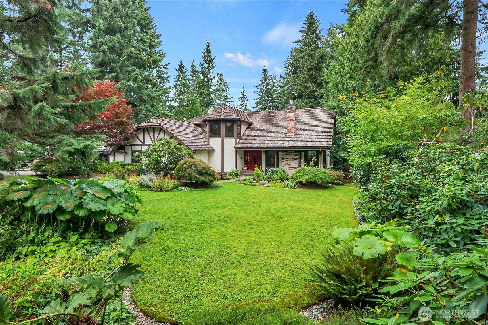 a view of a house with a big yard plants and large trees